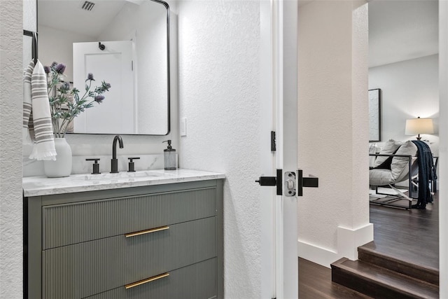 bathroom with visible vents, a textured wall, vanity, and wood finished floors