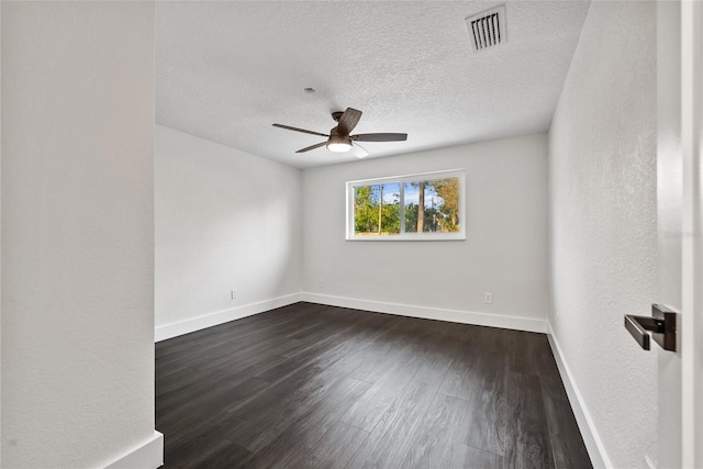 empty room featuring ceiling fan, a textured ceiling, dark wood-style flooring, visible vents, and baseboards