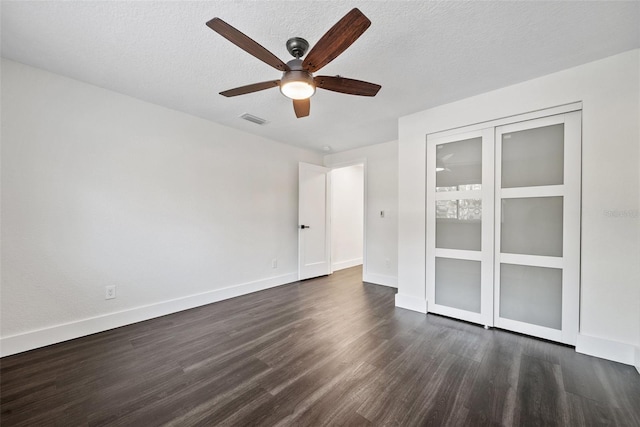 unfurnished bedroom with dark wood-style floors, baseboards, visible vents, and a textured ceiling