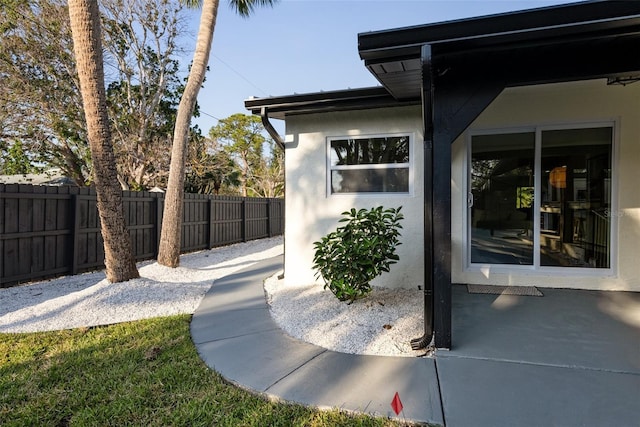 view of side of property featuring a patio, fence private yard, and stucco siding