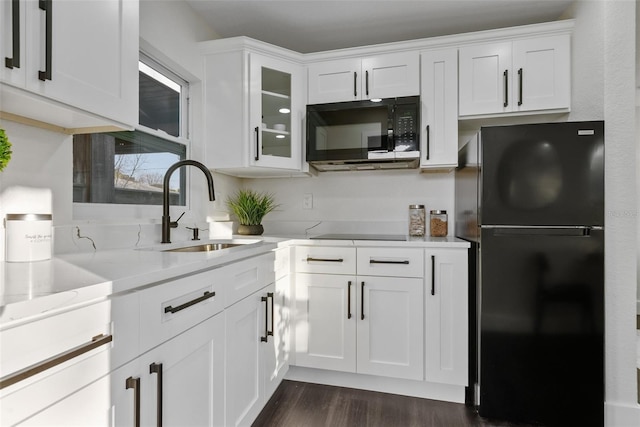 kitchen with dark wood-style floors, white cabinetry, a sink, and black appliances