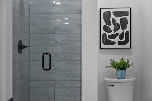 full bath featuring a textured wall, a stall shower, and toilet