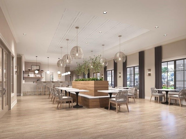 dining room with a raised ceiling, ornamental molding, and light wood-type flooring