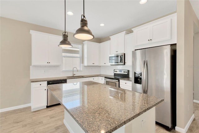 kitchen featuring sink, white cabinetry, hanging light fixtures, stainless steel appliances, and a kitchen island