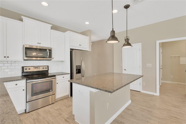 kitchen featuring pendant lighting, appliances with stainless steel finishes, dark stone counters, and white cabinets