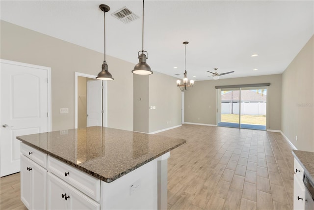 kitchen with white cabinetry, hanging light fixtures, and dark stone countertops