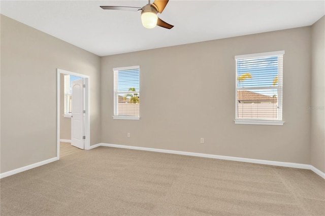 empty room featuring plenty of natural light, light colored carpet, and ceiling fan