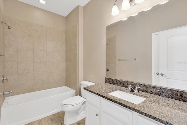 full bathroom with vanity, hardwood / wood-style flooring, toilet, and tiled shower / bath