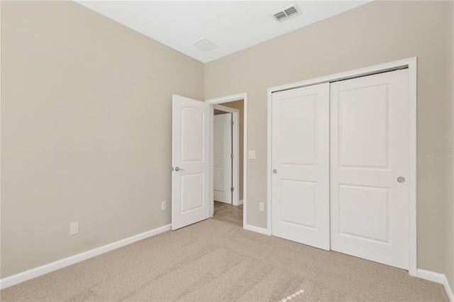 unfurnished bedroom featuring light carpet and a closet