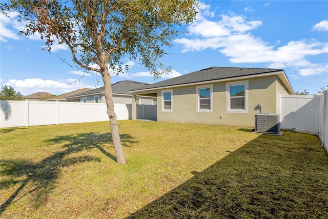 rear view of property featuring central AC and a lawn