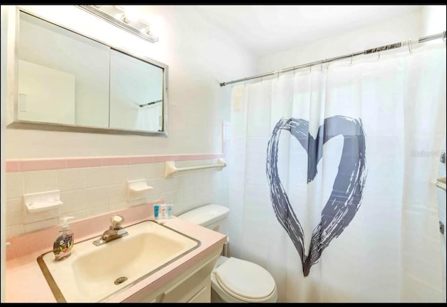 bathroom featuring vanity, toilet, a shower with shower curtain, and tile walls