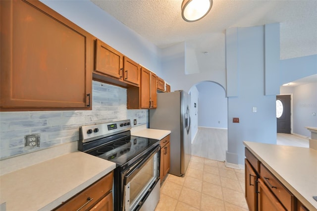 kitchen featuring stainless steel appliances, tasteful backsplash, light tile patterned floors, and a textured ceiling