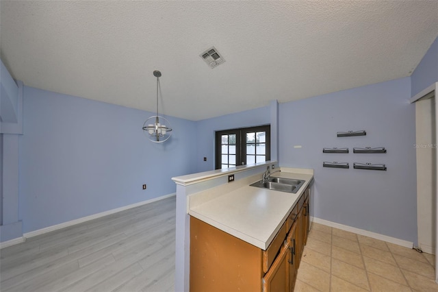 kitchen with french doors, sink, hanging light fixtures, and a textured ceiling