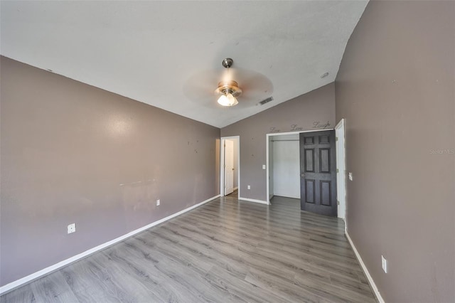 unfurnished bedroom featuring ceiling fan, vaulted ceiling, a closet, and light wood-type flooring