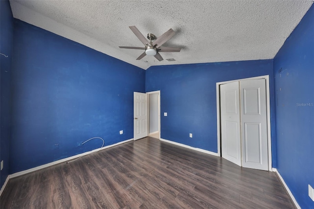 unfurnished bedroom featuring lofted ceiling, dark wood-type flooring, ceiling fan, a textured ceiling, and a closet