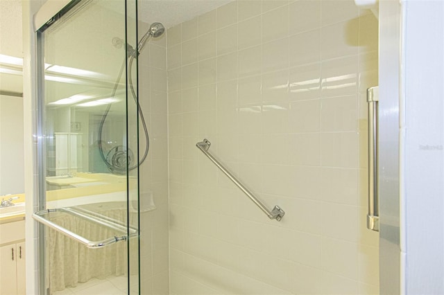 bathroom featuring a shower with door and vanity