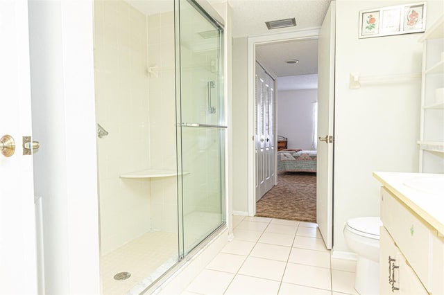 bathroom featuring vanity, toilet, tile patterned floors, and a shower with shower door