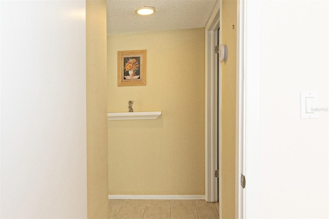 hall featuring light tile patterned floors and a textured ceiling