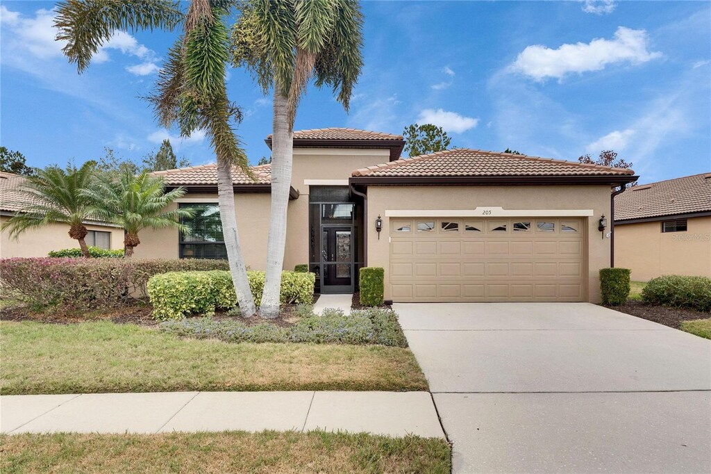205 Silver Falls Dr, Apollo Beach, FL 33572 - mediterranean / spanish house with a garage and a front lawn