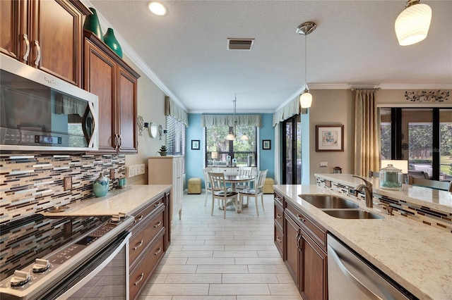 kitchen featuring sink, hanging light fixtures, stainless steel appliances, tasteful backsplash, and light stone countertops