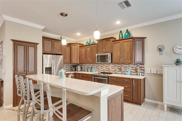 kitchen featuring light hardwood / wood-style flooring, appliances with stainless steel finishes, a center island with sink, a kitchen bar, and decorative light fixtures