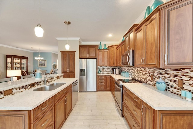 kitchen with appliances with stainless steel finishes, pendant lighting, an island with sink, sink, and a chandelier