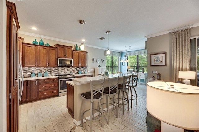 kitchen with pendant lighting, light hardwood / wood-style flooring, appliances with stainless steel finishes, a kitchen island with sink, and decorative backsplash