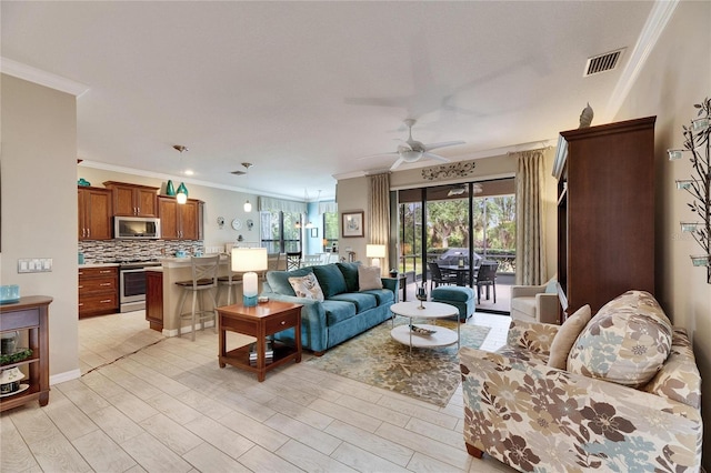 living room featuring ceiling fan, ornamental molding, and light hardwood / wood-style floors