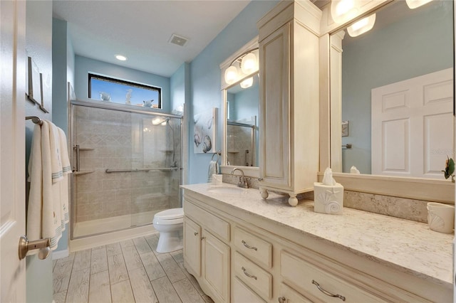 bathroom featuring vanity, an enclosed shower, and toilet