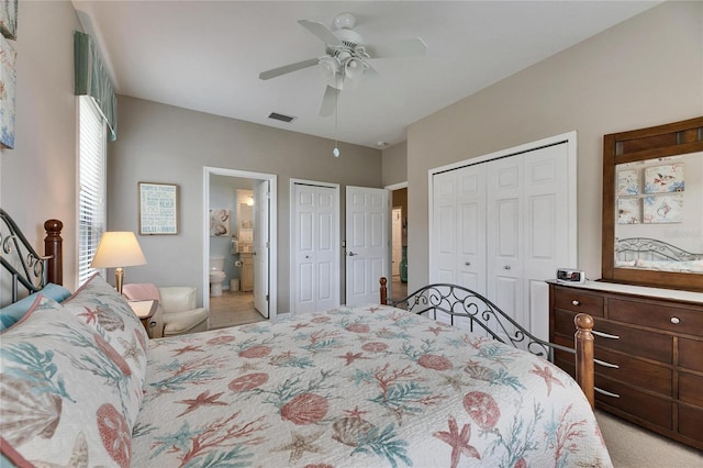 carpeted bedroom with ceiling fan, ensuite bathroom, and two closets