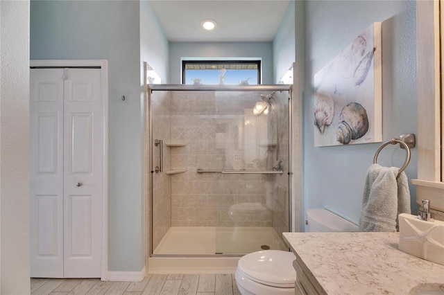 bathroom featuring toilet, hardwood / wood-style floors, vanity, and a shower with shower door