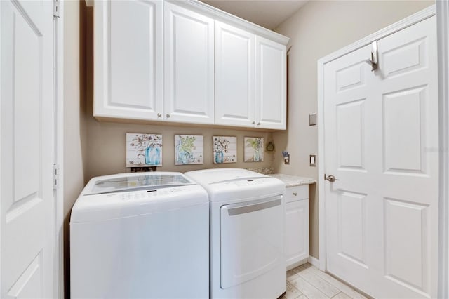 clothes washing area with cabinets and washing machine and clothes dryer