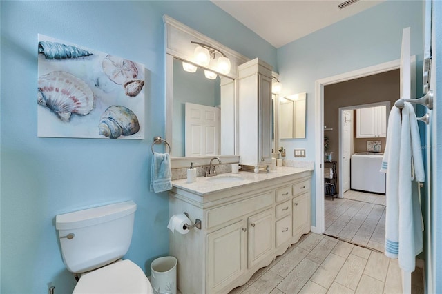 bathroom with vanity, washer / dryer, and toilet