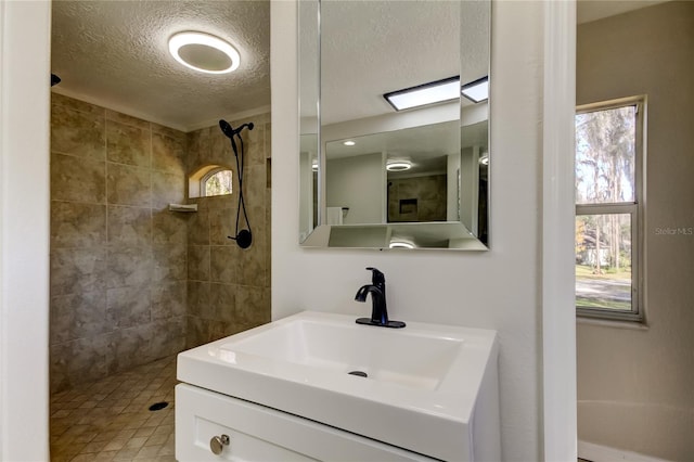 bathroom featuring tiled shower, a textured ceiling, and vanity