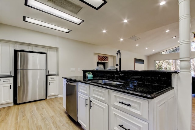 kitchen with appliances with stainless steel finishes, white cabinetry, dark stone counters, and light hardwood / wood-style flooring