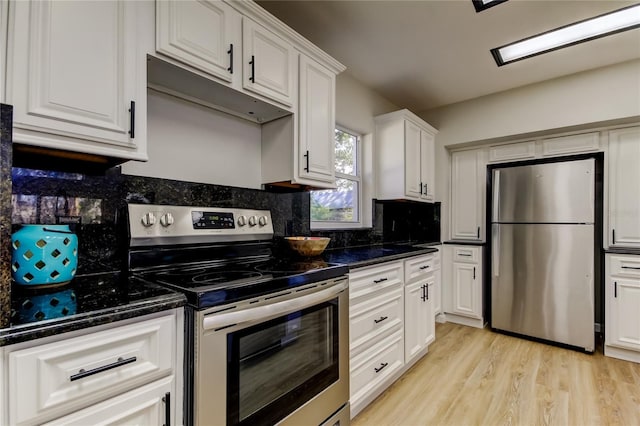 kitchen featuring white cabinetry, appliances with stainless steel finishes, dark stone countertops, and light hardwood / wood-style floors