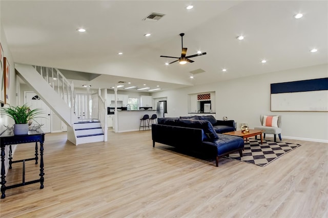 living room with ceiling fan, vaulted ceiling, and light hardwood / wood-style floors