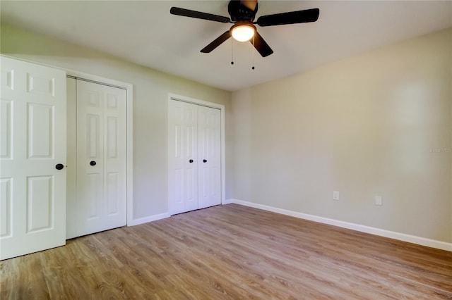 unfurnished bedroom featuring light hardwood / wood-style flooring, ceiling fan, and multiple closets