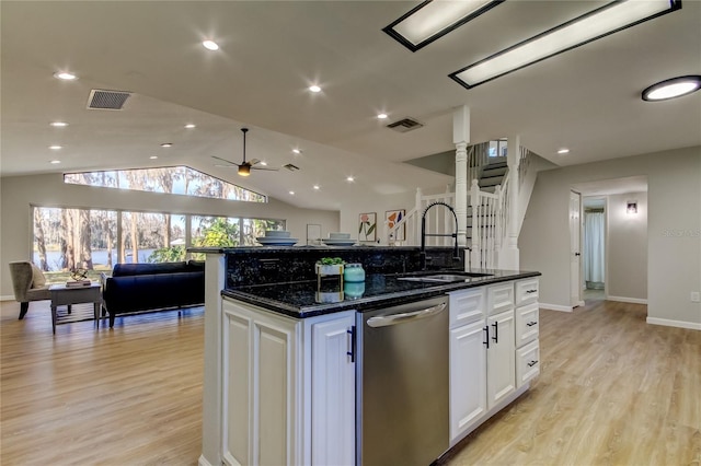 kitchen featuring stainless steel dishwasher, sink, white cabinetry, a kitchen island with sink, and dark stone countertops