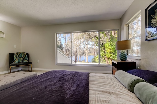 bedroom with a water view and a textured ceiling