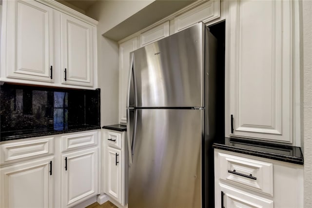 kitchen featuring dark stone counters, white cabinetry, and stainless steel fridge