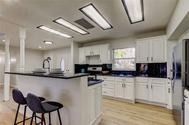 kitchen with a center island with sink, appliances with stainless steel finishes, white cabinets, and a breakfast bar area