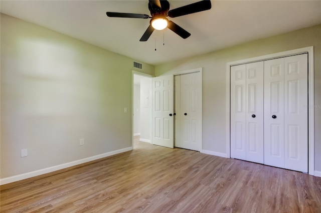 unfurnished bedroom featuring light wood-type flooring, ceiling fan, and two closets