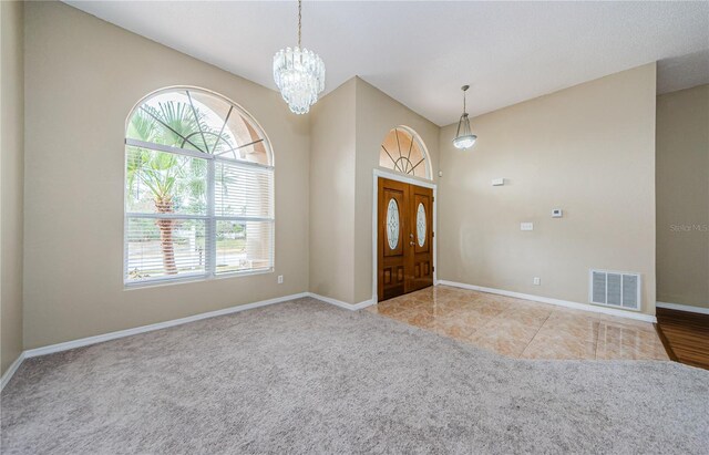 foyer with a notable chandelier and light colored carpet