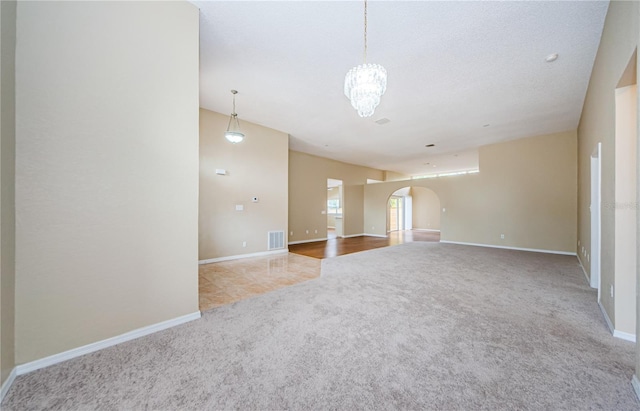 carpeted empty room with a textured ceiling and a chandelier