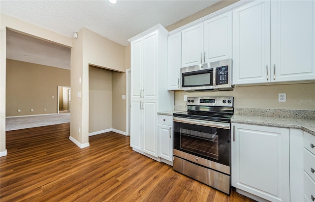 kitchen featuring light stone counters, stainless steel appliances, and white cabinets