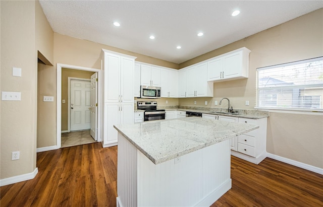 kitchen with a kitchen island, appliances with stainless steel finishes, sink, and white cabinets