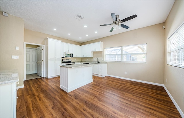 kitchen with sink, appliances with stainless steel finishes, dark hardwood / wood-style flooring, a kitchen island, and white cabinets