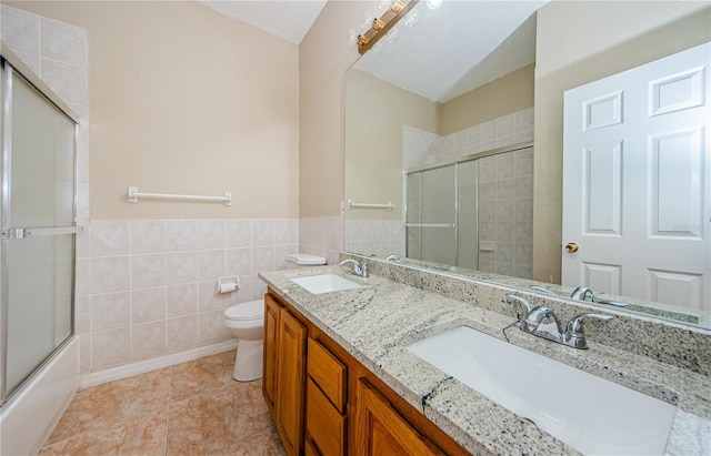 full bathroom with toilet, combined bath / shower with glass door, tile walls, vanity, and tile patterned flooring