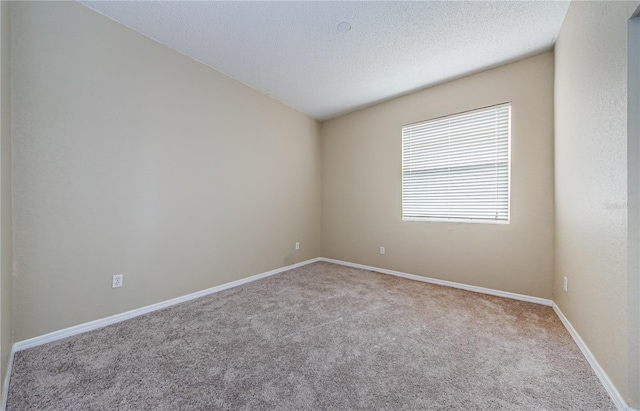 spare room with light colored carpet and a textured ceiling